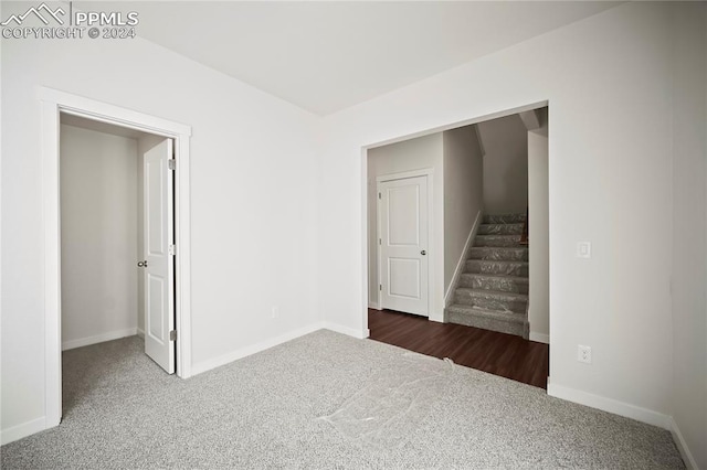 unfurnished room featuring baseboards, stairs, and dark carpet