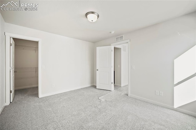 unfurnished bedroom featuring carpet floors, a walk in closet, visible vents, and baseboards