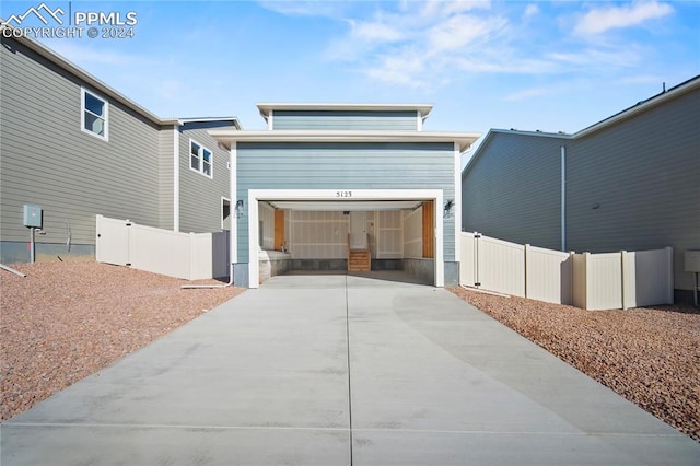 view of front of house with a garage, concrete driveway, and fence