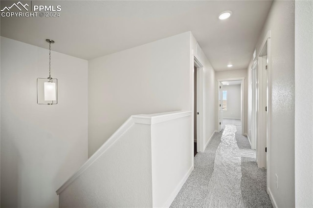 hallway with an upstairs landing, recessed lighting, baseboards, and light colored carpet