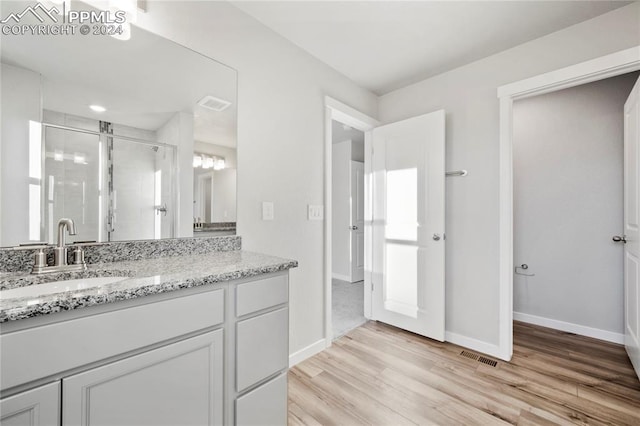 bathroom with hardwood / wood-style floors, vanity, and an enclosed shower