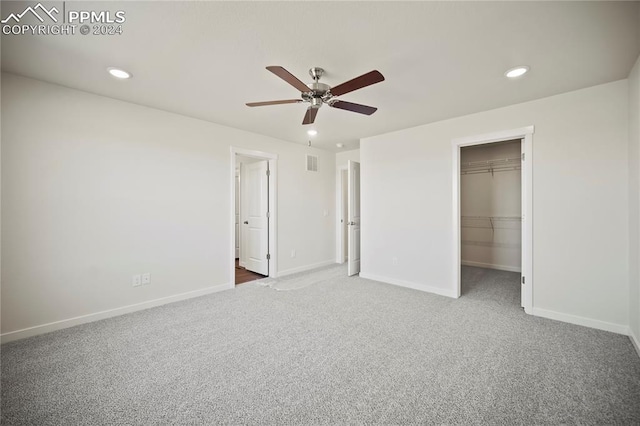 unfurnished bedroom with carpet, baseboards, a walk in closet, and recessed lighting