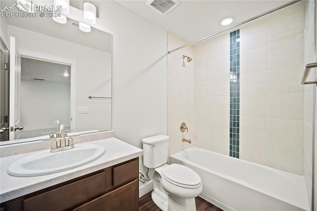 full bathroom featuring vanity, wood-type flooring, tiled shower / bath combo, and toilet