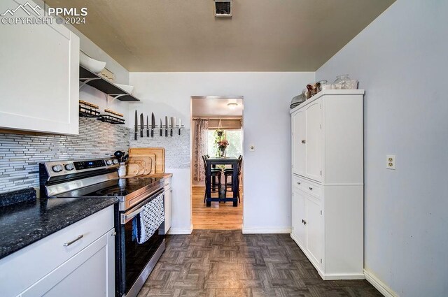 kitchen featuring tasteful backsplash, white cabinets, dark parquet floors, stainless steel electric stove, and dark stone countertops