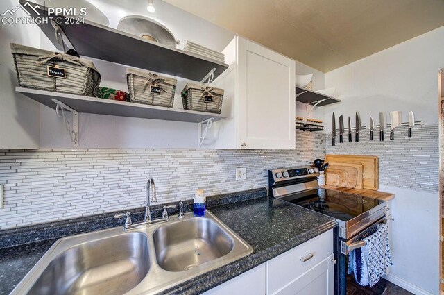 kitchen with stainless steel range with electric cooktop, sink, white cabinets, and backsplash