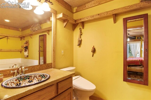 bathroom with toilet, vanity, and a textured ceiling