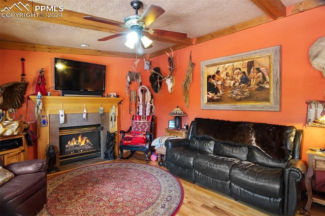 living room with ceiling fan, wood-type flooring, a high end fireplace, and a textured ceiling