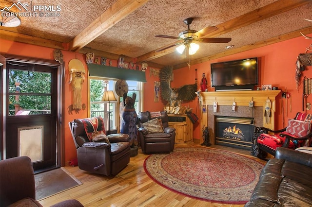 living room with a textured ceiling, wood-type flooring, beam ceiling, and ceiling fan