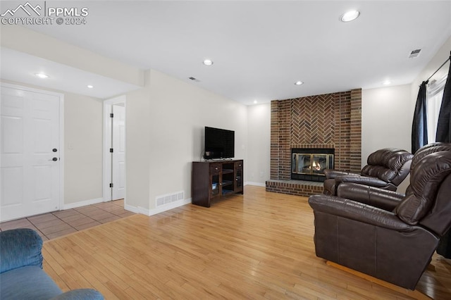 living room featuring light hardwood / wood-style floors, a barn door, brick wall, and a brick fireplace