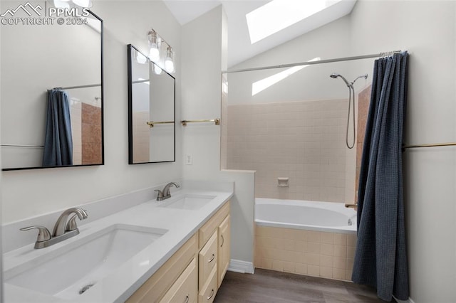 bathroom with lofted ceiling with skylight, tiled shower / bath, hardwood / wood-style flooring, and vanity