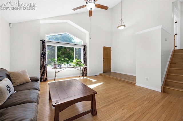 living room with light hardwood / wood-style flooring, ceiling fan, and high vaulted ceiling