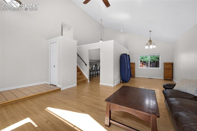 living room with light hardwood / wood-style floors, ceiling fan with notable chandelier, and high vaulted ceiling