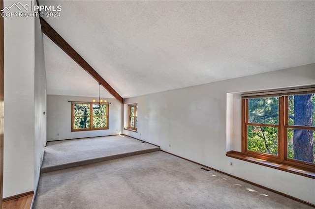 carpeted empty room with a notable chandelier, a textured ceiling, and vaulted ceiling with beams