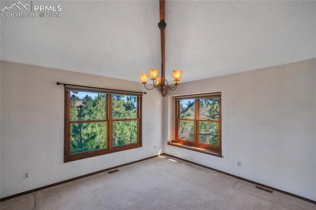 spare room featuring a notable chandelier, a textured ceiling, carpet flooring, and lofted ceiling