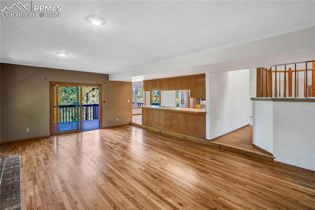 unfurnished living room with light hardwood / wood-style floors and a textured ceiling