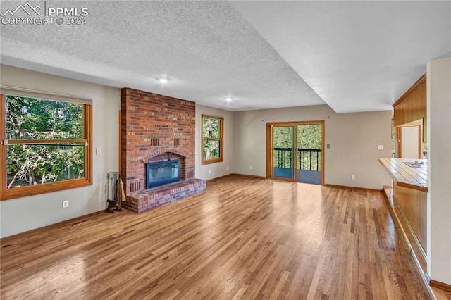 unfurnished living room with a textured ceiling, a fireplace, and light hardwood / wood-style floors