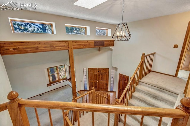 stairs featuring carpet flooring, a notable chandelier, and a textured ceiling