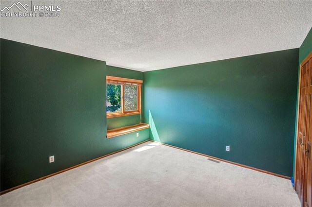 carpeted empty room featuring a textured ceiling