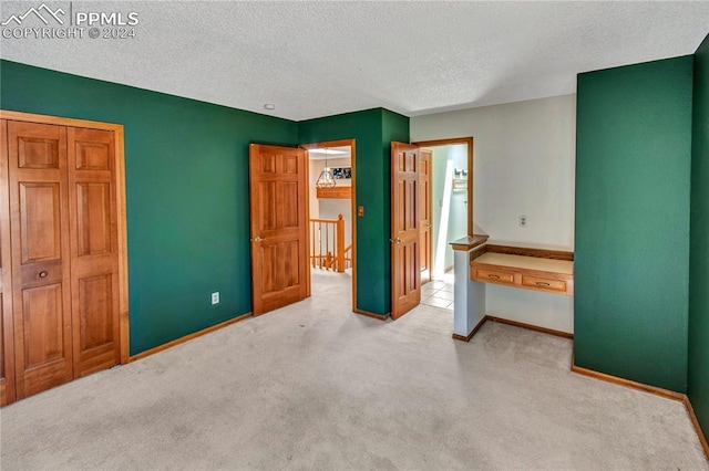 unfurnished bedroom with light colored carpet and a textured ceiling