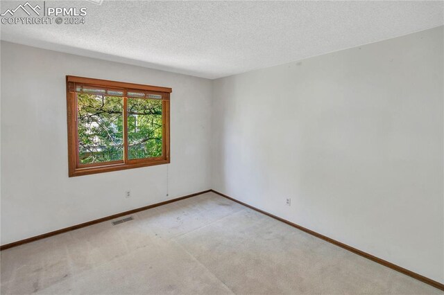 empty room with a textured ceiling and carpet floors