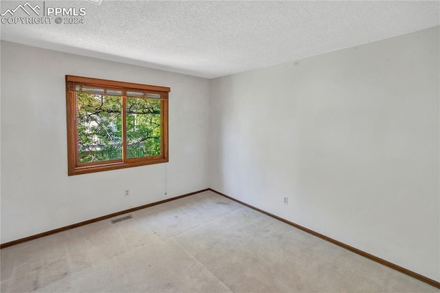 carpeted empty room with a textured ceiling