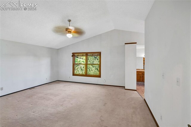 spare room featuring lofted ceiling, light carpet, and ceiling fan