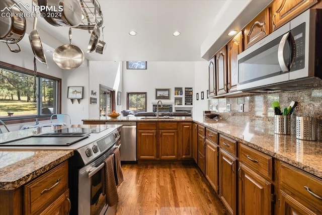 kitchen with sink, tasteful backsplash, light wood-type flooring, appliances with stainless steel finishes, and light stone countertops