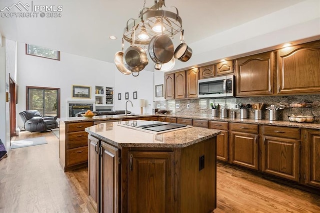 kitchen with black electric cooktop, a kitchen island, kitchen peninsula, and decorative backsplash