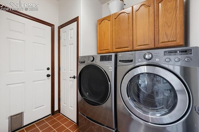 laundry room featuring cabinets, washing machine and dryer, and dark tile patterned flooring