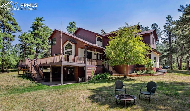 rear view of house featuring a yard, a deck, and an outdoor fire pit