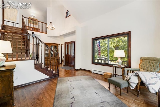 entrance foyer featuring a baseboard heating unit, wood-type flooring, high vaulted ceiling, and a chandelier