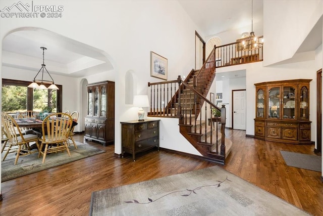 entrance foyer with dark wood-type flooring, an inviting chandelier, and a tray ceiling