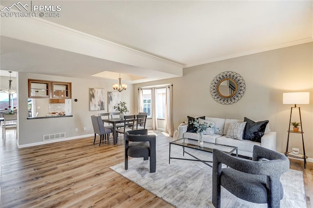 living room featuring crown molding, a chandelier, and wood-type flooring