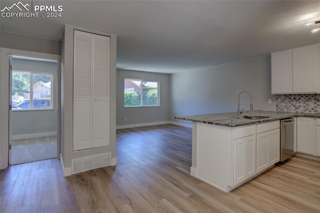 kitchen featuring tasteful backsplash, white cabinetry, dishwasher, sink, and kitchen peninsula