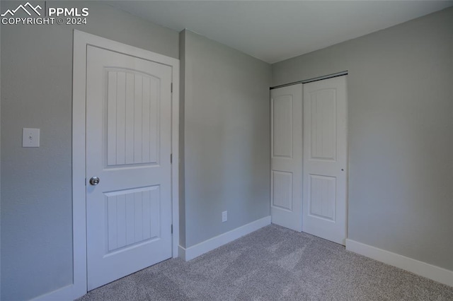 unfurnished bedroom featuring light colored carpet and a closet