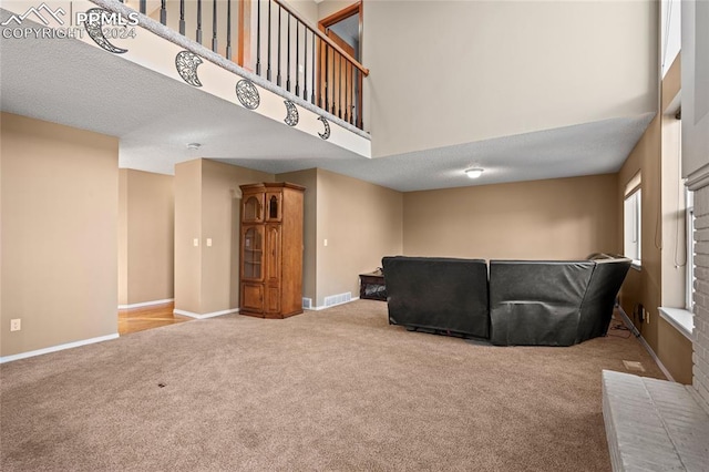 living room featuring carpet, a towering ceiling, and a textured ceiling