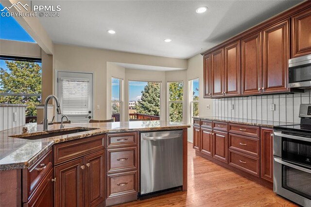 kitchen featuring light hardwood / wood-style flooring, tasteful backsplash, light stone counters, sink, and stainless steel appliances