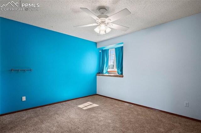 spare room featuring a textured ceiling, carpet flooring, and ceiling fan