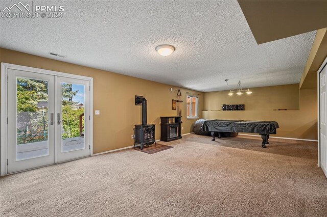 bedroom featuring carpet, a textured ceiling, access to exterior, and a wood stove