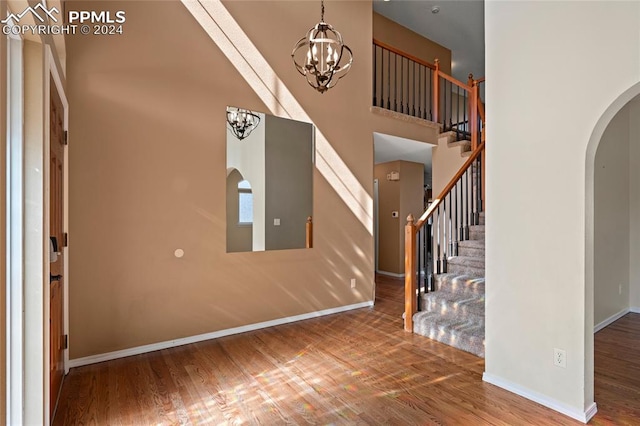 foyer with hardwood / wood-style floors, a high ceiling, and a notable chandelier