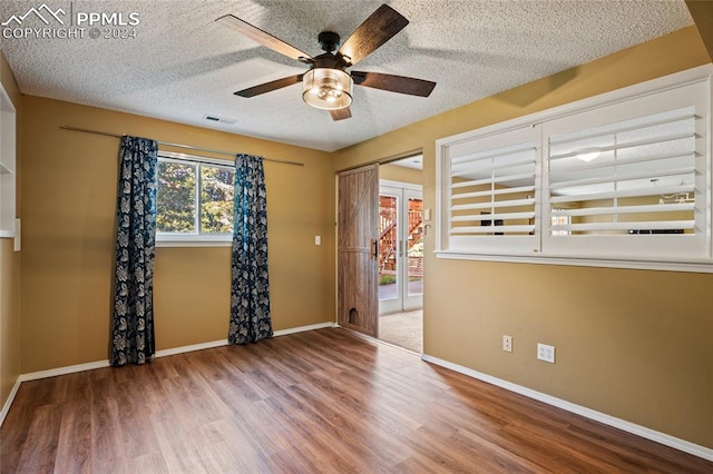 spare room with ceiling fan, a textured ceiling, and wood-type flooring