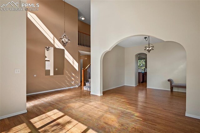 foyer featuring hardwood / wood-style floors, high vaulted ceiling, and an inviting chandelier