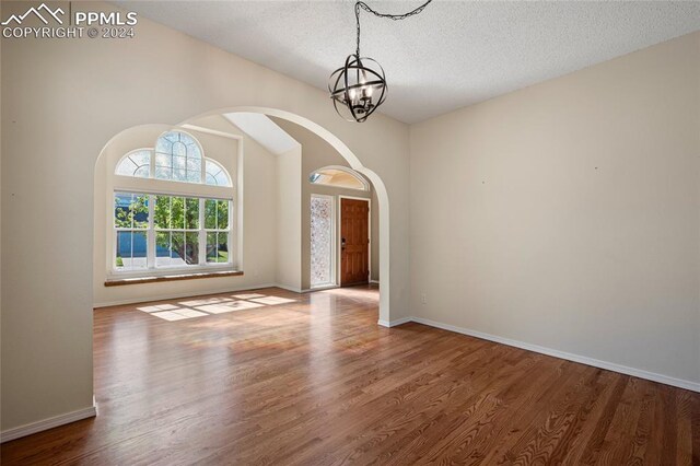 interior space with a textured ceiling, hardwood / wood-style floors, and a chandelier