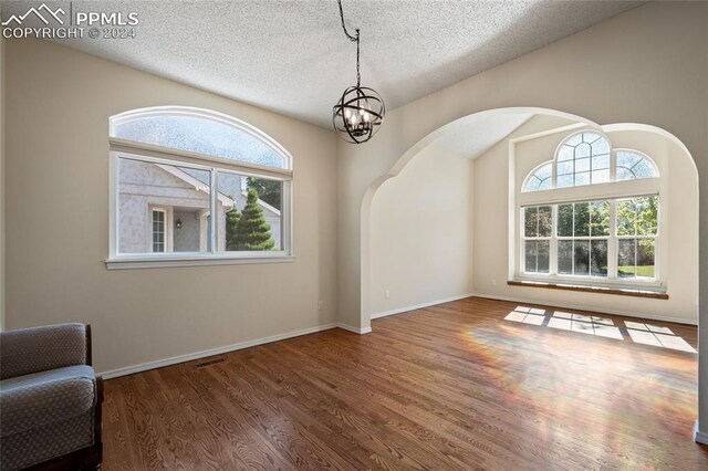 interior space with wood-type flooring, a notable chandelier, and a textured ceiling