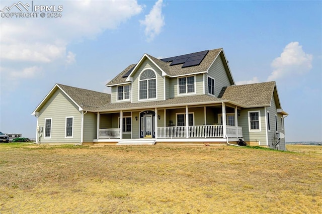 view of front of property featuring a front yard, a porch, solar panels, and roof with shingles
