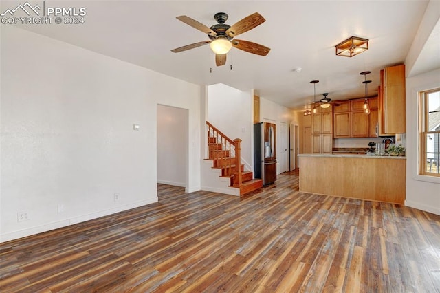 unfurnished living room with a ceiling fan, wood finished floors, and stairs
