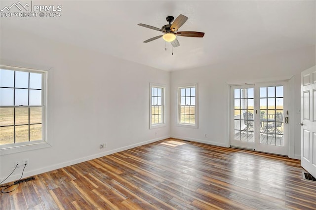 unfurnished room with ceiling fan, baseboards, visible vents, and wood finished floors