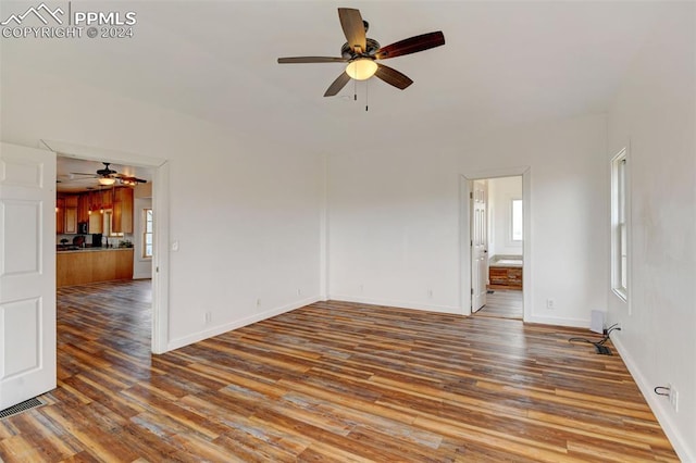 empty room with wood finished floors, baseboards, a ceiling fan, and visible vents