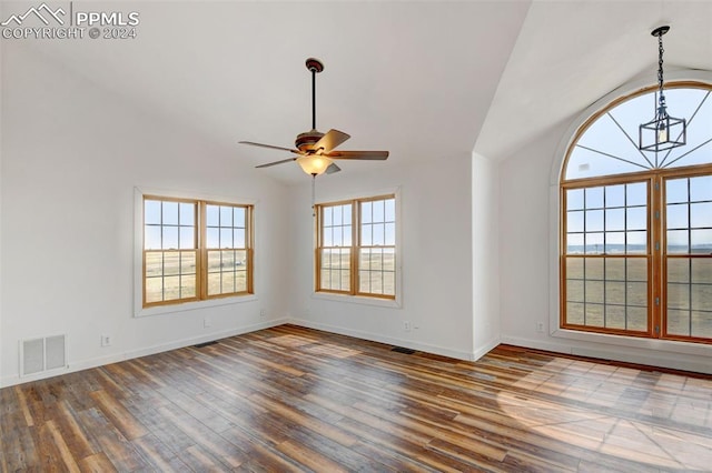 empty room featuring wood finished floors, ceiling fan, vaulted ceiling, and visible vents
