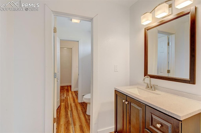 bathroom with vanity, baseboards, toilet, and wood finished floors